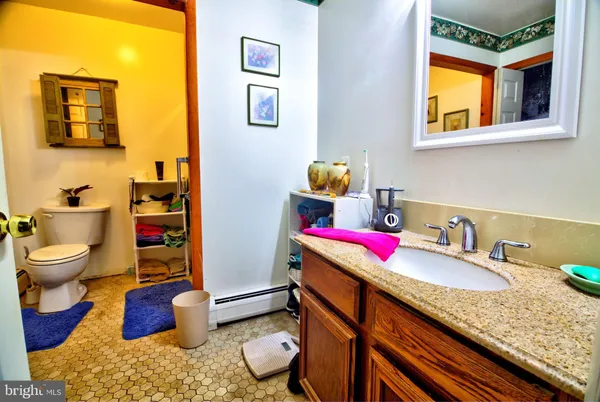 a bathroom with a granite countertop toilet sink and mirror