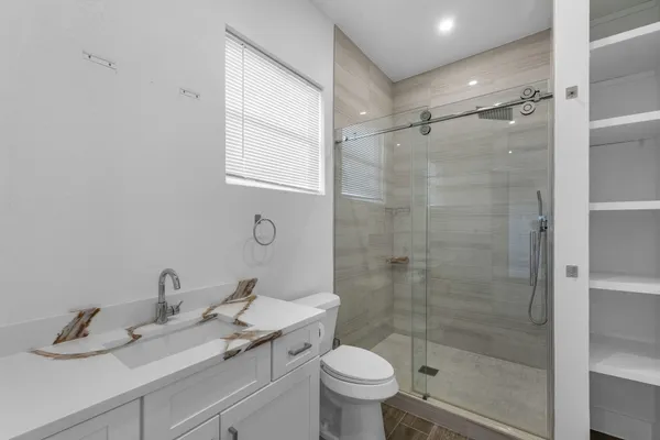 a bathroom with a shower sink vanity mirror and toilet