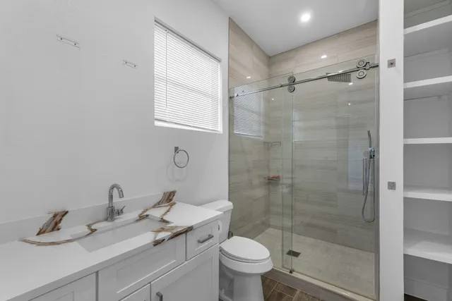 a bathroom with a shower sink vanity mirror and toilet