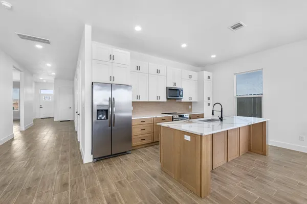 a kitchen with stainless steel appliances a sink a stove a refrigerator and cabinets