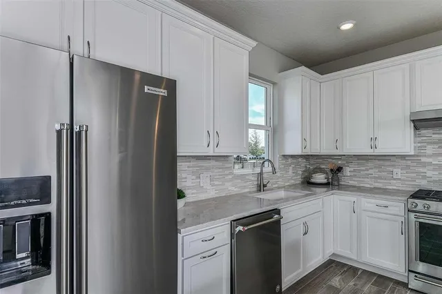 a kitchen with stainless steel appliances granite countertop a refrigerator sink and stove