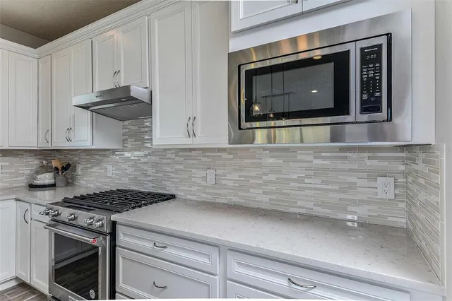 a kitchen with stainless steel appliances white cabinets and a stove top oven