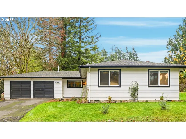 a white house that has a small yard and a large window