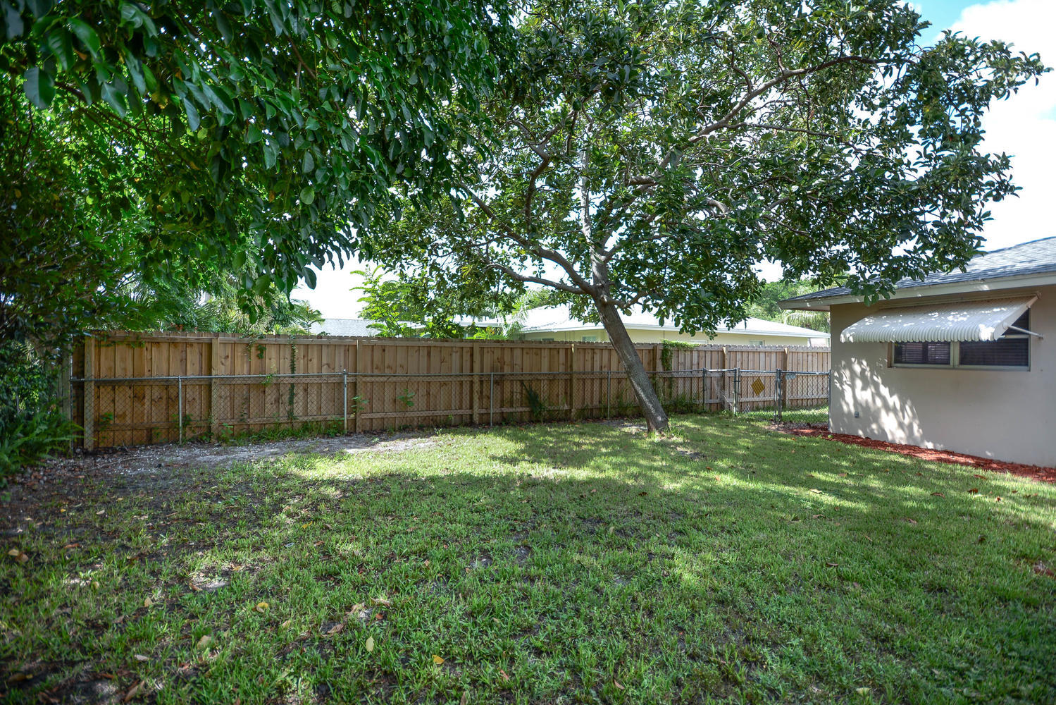 493 Dover Road Tequesta, FL 33469 - Photo 3 of 33 a view of a backyard with a trees and wooden fence