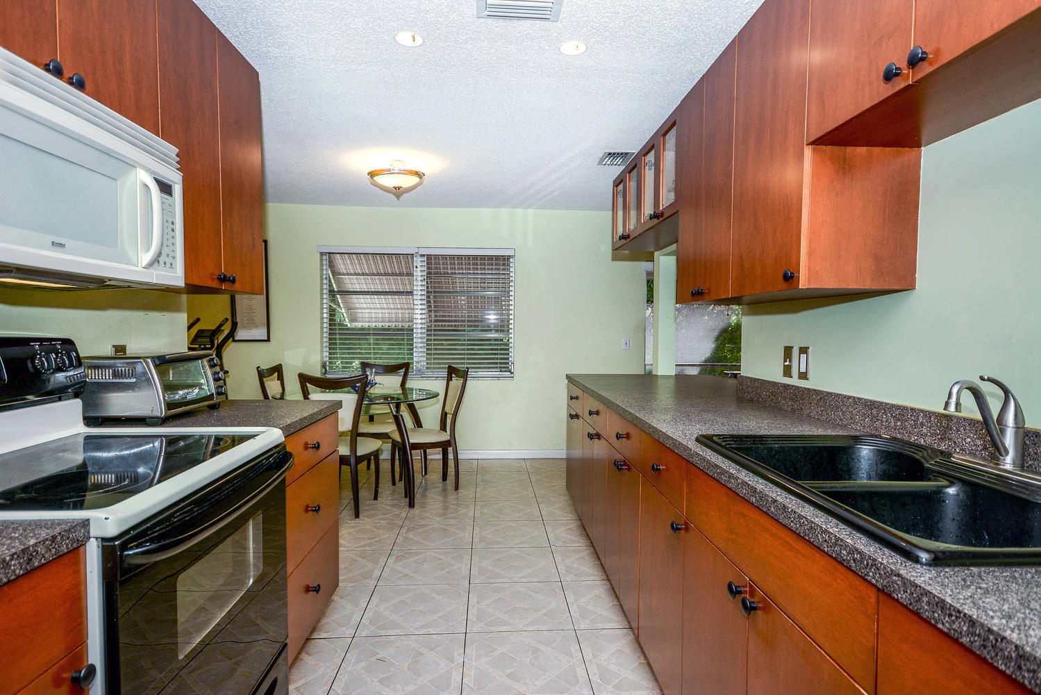 493 Dover Road Tequesta, FL 33469 - Photo 7 of 33 a kitchen with stainless steel appliances a sink stove and cabinets