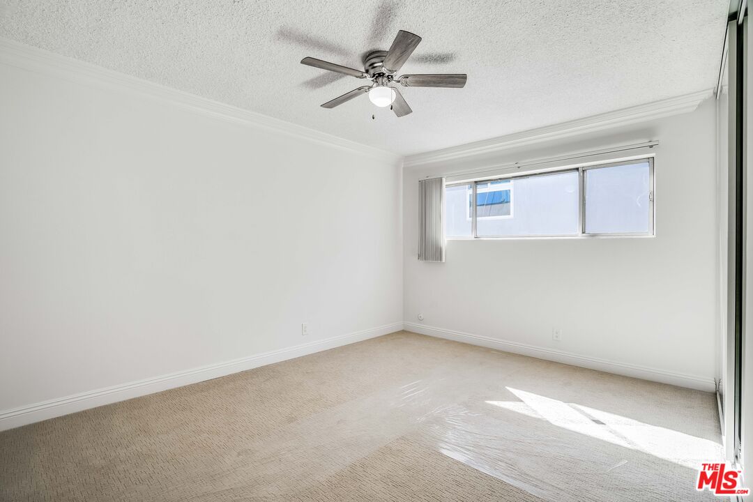 7548 Hampton Avenue, Unit 304 West Hollywood, CA 90046 - Photo 10 of 23 an empty room with a ceiling fan and window