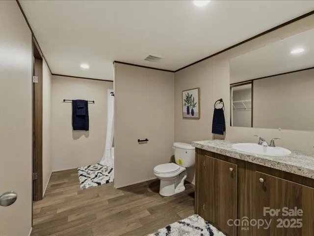 a bathroom with a granite countertop sink a toilet and mirror