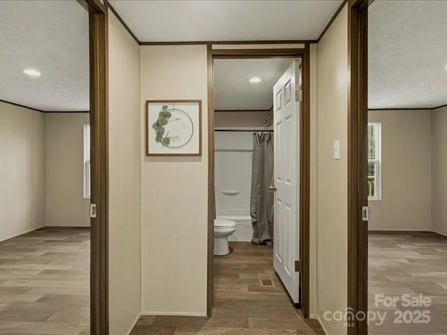 a view of a hallway with wooden floor and a bathroom