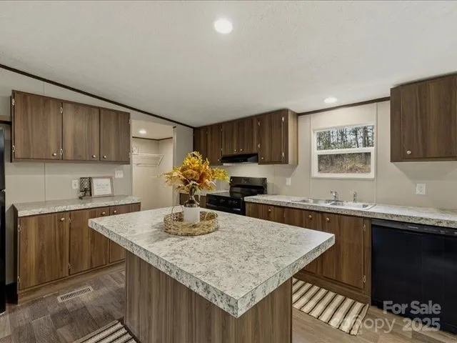 a kitchen with kitchen island granite countertop a sink and cabinets
