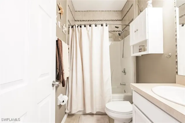 a bathroom with a granite countertop bathtub shower sink vanity and toilet