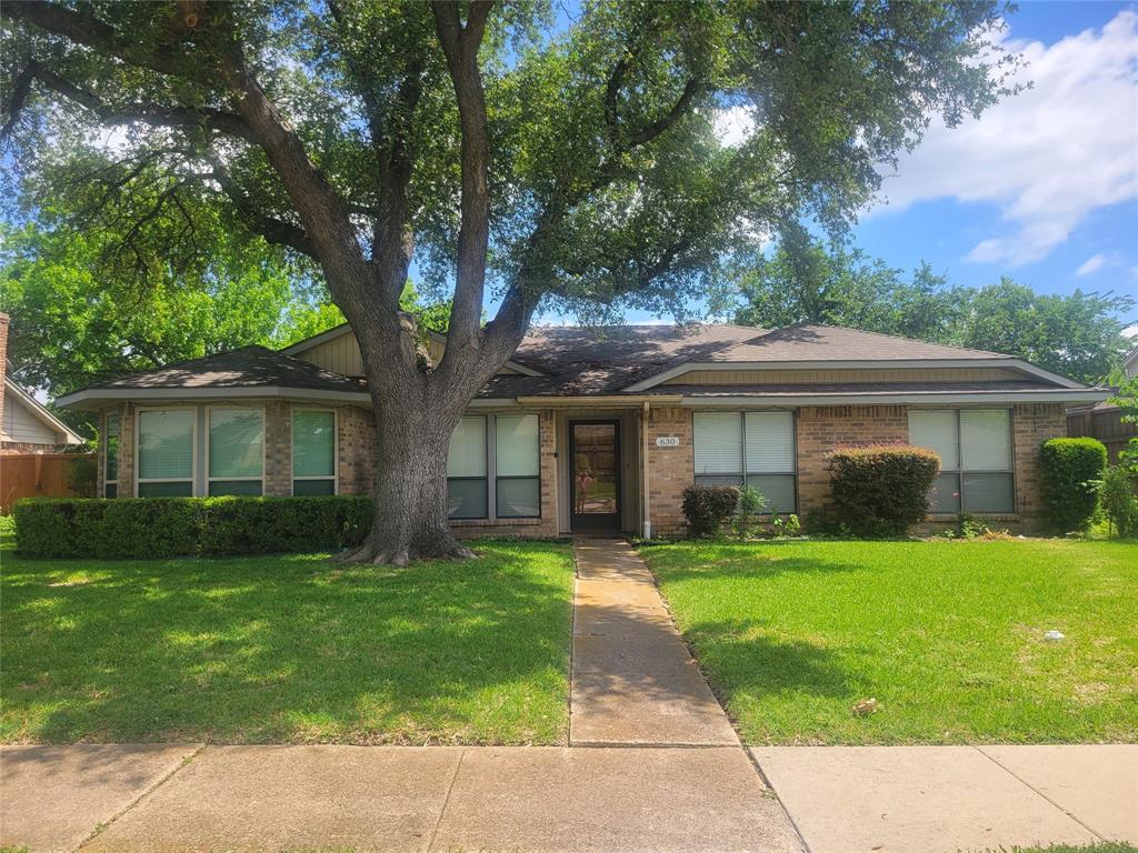630 Country View Lane Garland, TX 75043 - Photo 1 of 29 Brick exterior home featuring a prominent mature tree, a neatly manicured lawn, and a sidewalk entrance path