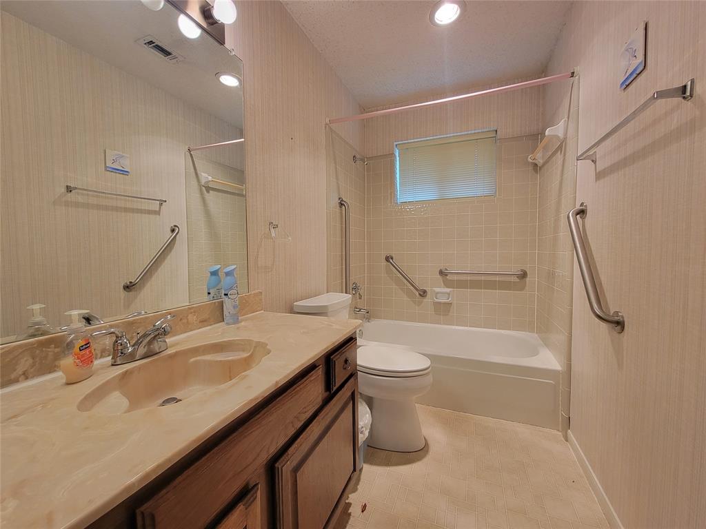 630 Country View Lane Garland, TX 75043 - Photo 21 of 29 Bathroom featuring a wood-finish vanity with an integrated countertop sink, full-width mirror, and overhead vanity lighting