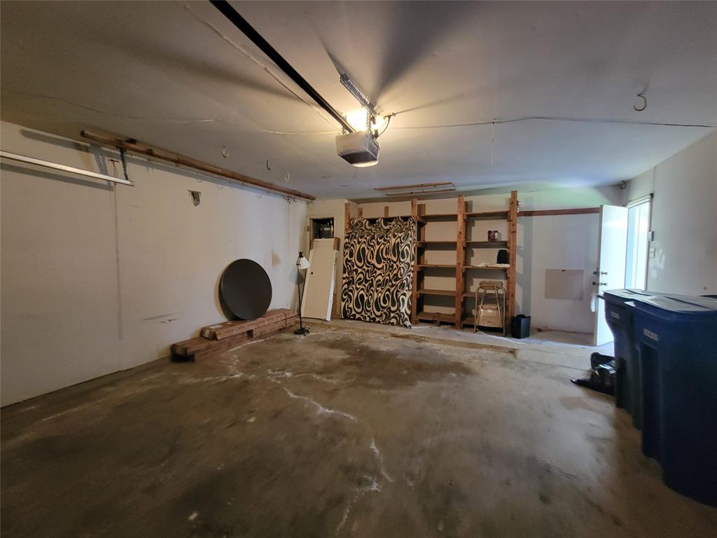 630 Country View Lane Garland, TX 75043 - Photo 26 of 29 Spacious garage featuring concrete flooring, an automatic garage door opener, and built-in wood shelving for organized storage