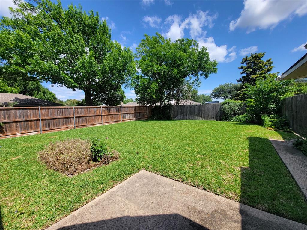 630 Country View Lane Garland, TX 75043 - Photo 27 of 29 Spacious backyard featuring a large grassy area, wooden privacy fencing, and mature trees providing natural shade