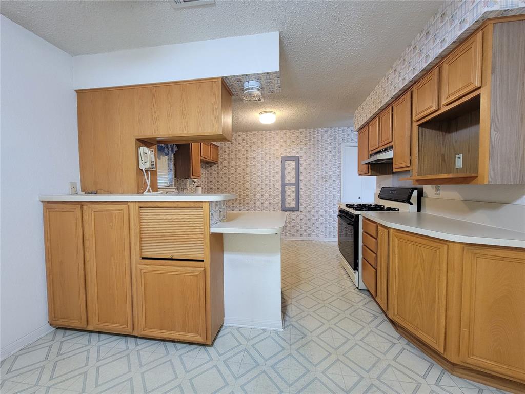 630 Country View Lane Garland, TX 75043 - Photo 10 of 29 Kitchen featuring extensive wood cabinetry, light countertops, and a built-in breakfast bar