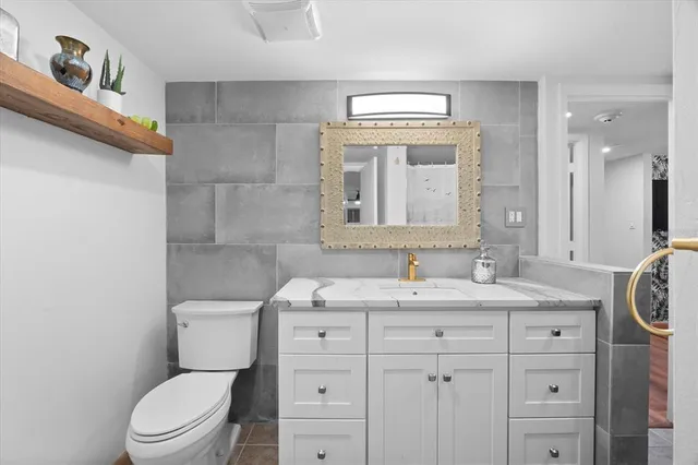 a bathroom with a granite countertop toilet sink and mirror
