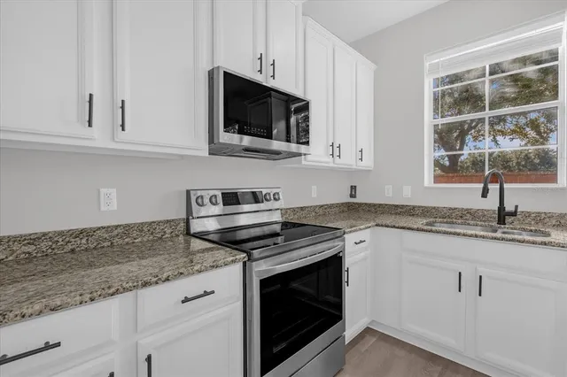 a kitchen with granite countertop white cabinets and a stove