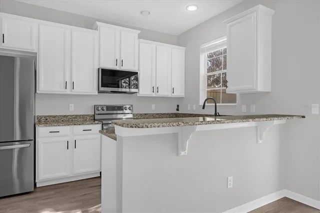 a kitchen with stainless steel appliances granite countertop a stove a sink and a microwave