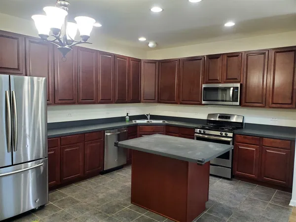 a kitchen with wooden cabinets stainless steel appliances and a center island