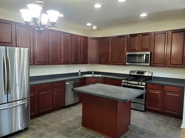 a kitchen with wooden cabinets stainless steel appliances and a center island