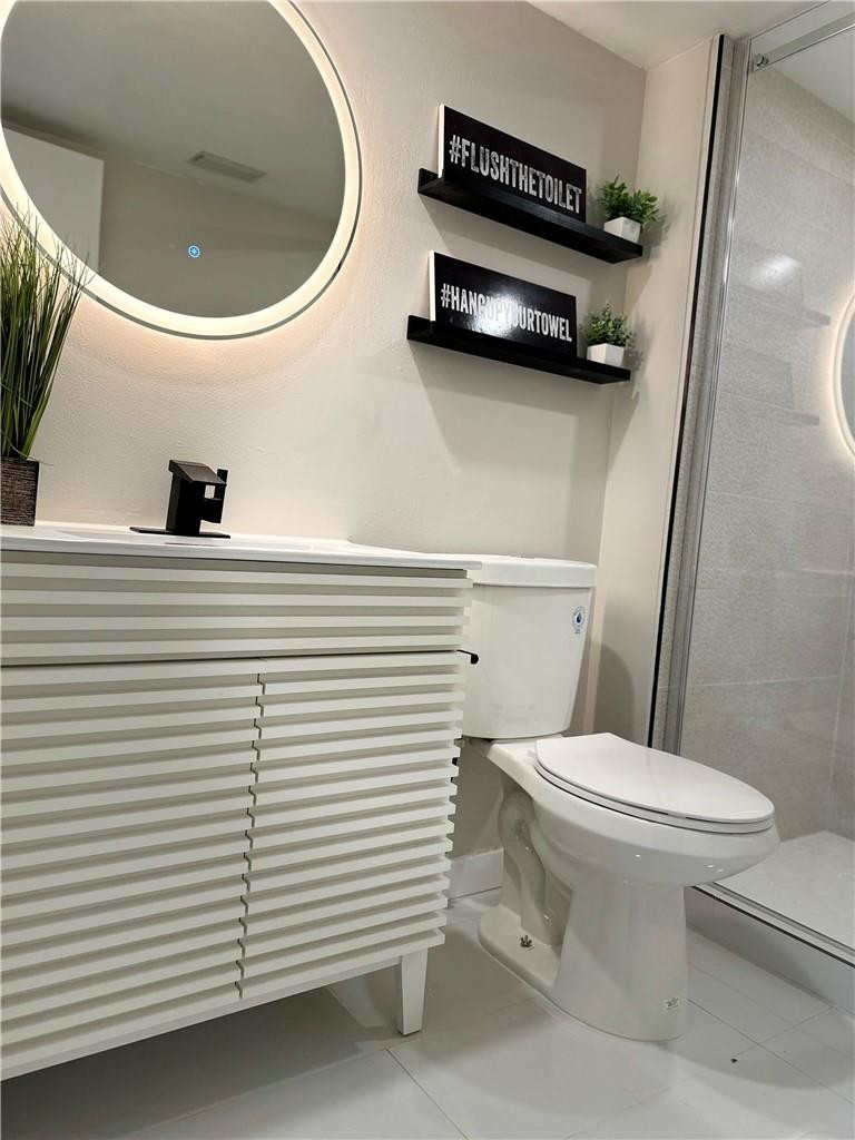 8801 Wiles Road, Unit 207 Coral Springs, FL 33067 - Photo 14 of 31 a bathroom with a sink a toilet and a mirror