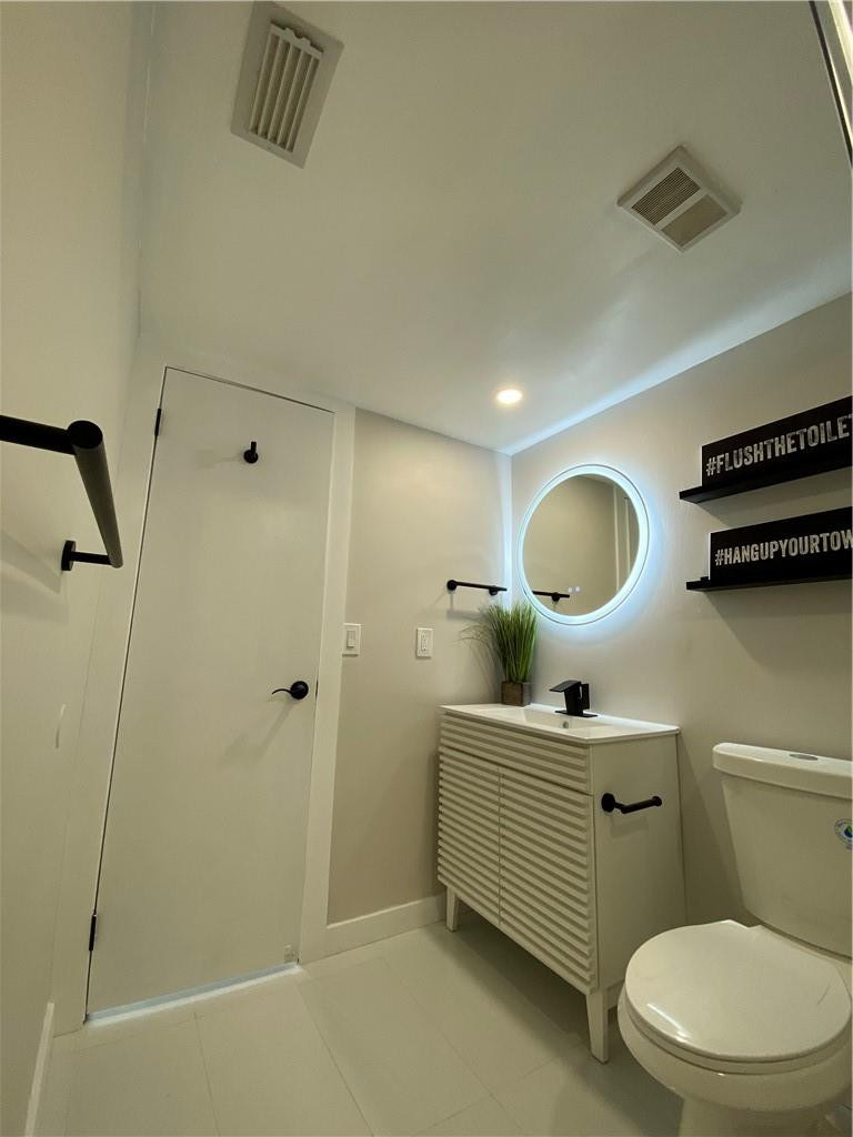 8801 Wiles Road, Unit 207 Coral Springs, FL 33067 - Photo 17 of 31 a bathroom with a toilet a sink and mirror