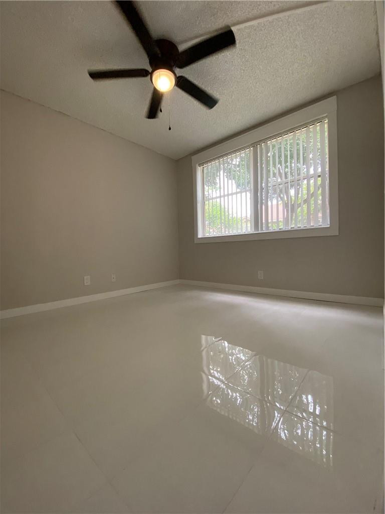 8801 Wiles Road, Unit 207 Coral Springs, FL 33067 - Photo 19 of 31 en empty room with windows and chandelier fan