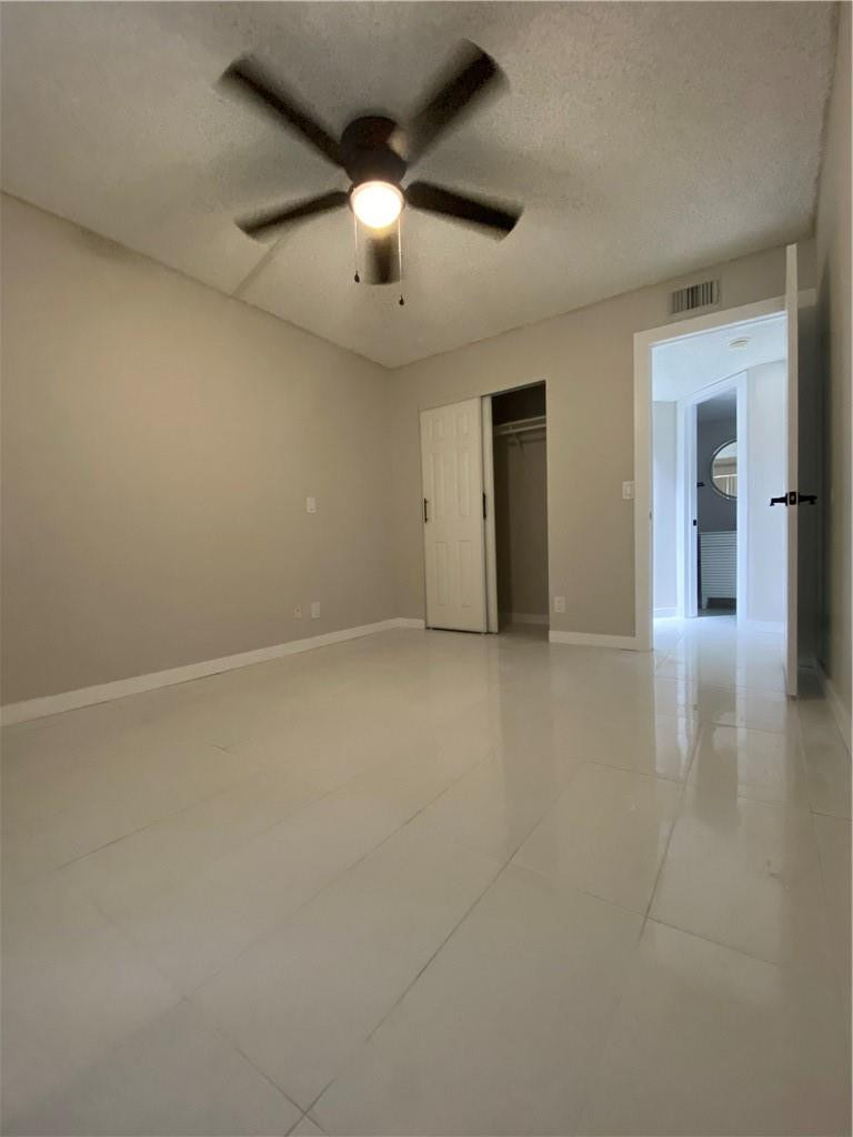 8801 Wiles Road, Unit 207 Coral Springs, FL 33067 - Photo 20 of 31 an empty room with chandelier fan and windows