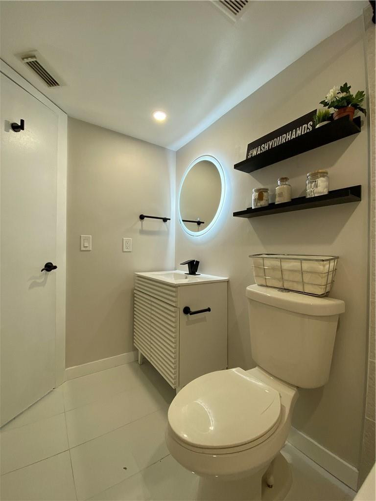 8801 Wiles Road, Unit 207 Coral Springs, FL 33067 - Photo 28 of 31 a bathroom with a toilet a sink and mirror