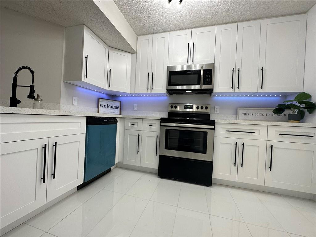 8801 Wiles Road, Unit 207 Coral Springs, FL 33067 - Photo 3 of 31 a kitchen with white cabinets and stainless steel appliances