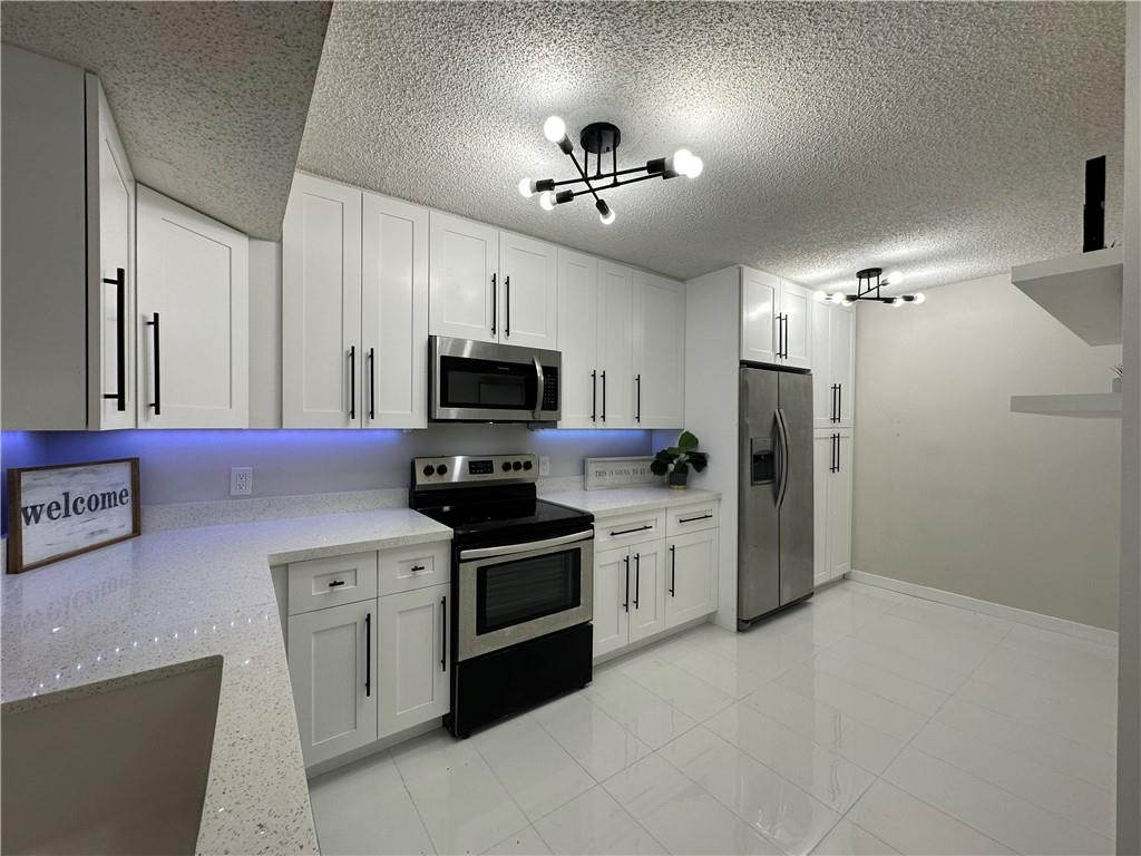8801 Wiles Road, Unit 207 Coral Springs, FL 33067 - Photo 5 of 31 a kitchen with stainless steel appliances a stove a sink cabinets and a refrigerator