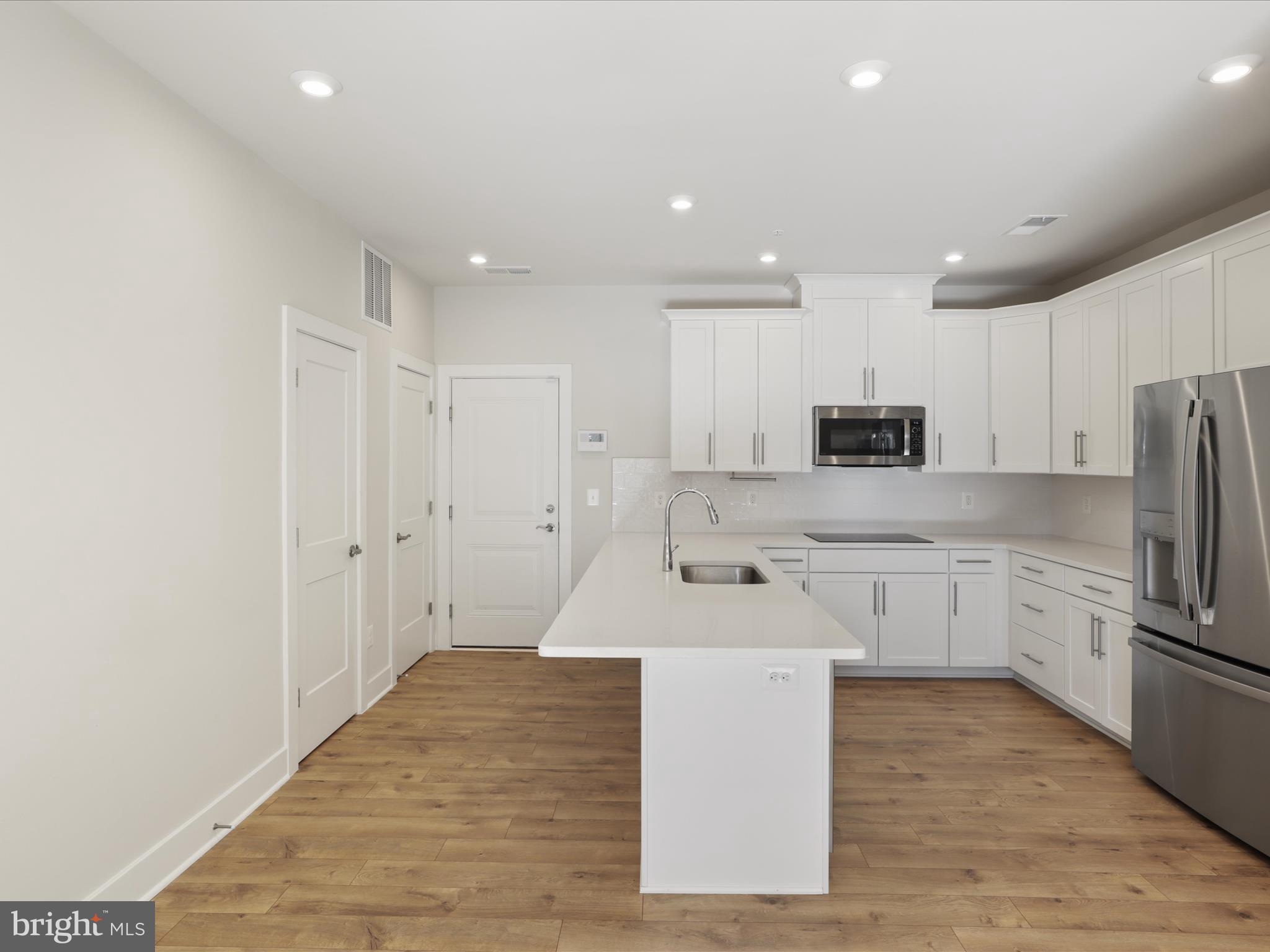 1696 Bandit Loop Reston, VA 20190 - Photo 7 of 38 a large kitchen with kitchen island a sink a stove a refrigerator and white cabinets
