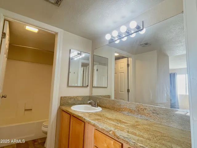 a bathroom with a granite countertop sink a mirror and a shower