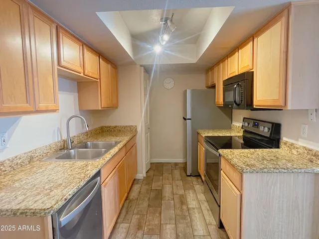 a kitchen with granite countertop wooden cabinets a sink and dishwasher