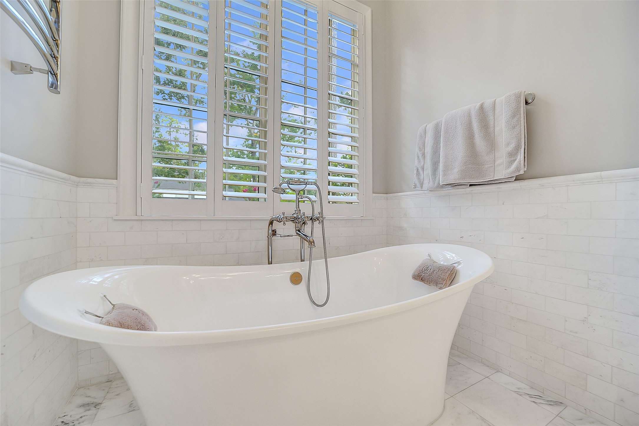 252 Piney Point Road Houston, TX 77024 - Photo 18 of 46 Luxurious marble tile wainscot lends texture and elegance to the space framing a Victor + Albert white slipper tub.