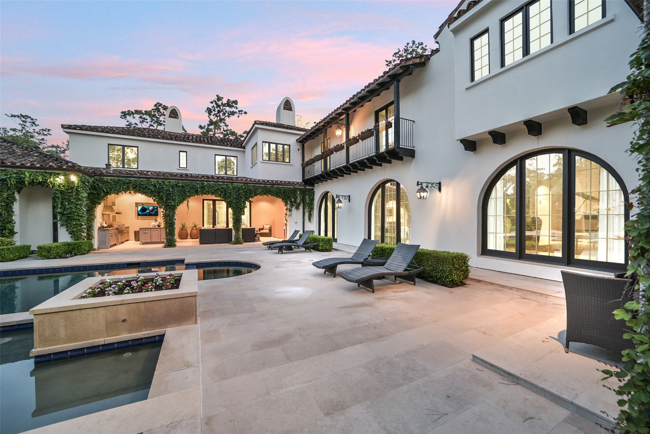 252 Piney Point Road Houston, TX 77024 - Photo 33 of 46 Additional view of the backyard oasis reveals the striking Palladian-style windows lining the rear facade as well as the loggia featuring a fully equipped summer kitchen and outdoor fireplace.