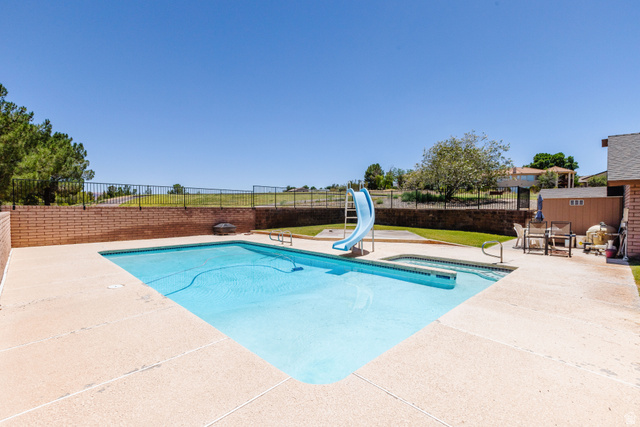 1470 Redwood Tree Street St. George, UT 84790 - Photo 52 of 53 Expansive backyard featuring a geometric in-ground pool with integrated spa, a light-toned concrete patio, and a brick retaining wall