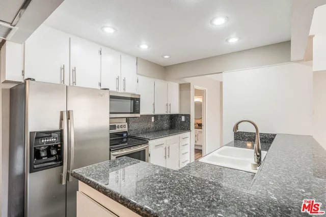 a kitchen with granite countertop a refrigerator and a sink
