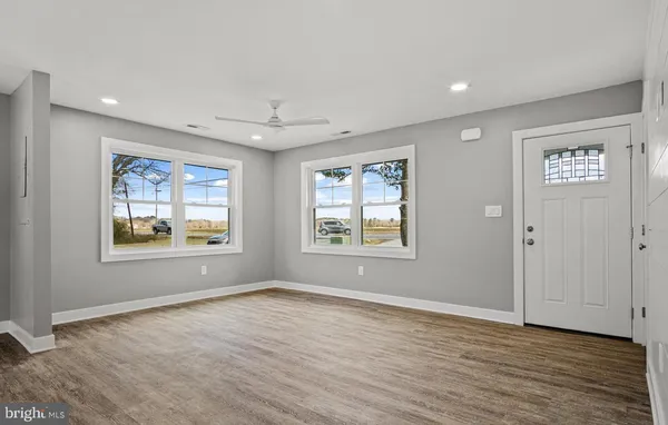 a view of an empty room with a window and wooden floor