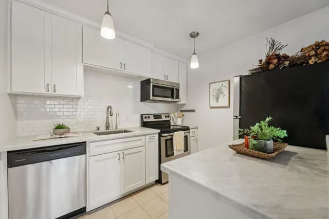 a kitchen with stainless steel appliances kitchen island a white counter top space a sink a stove and white cabinets