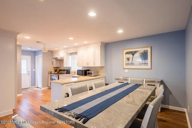 a living room with stainless steel appliances kitchen island granite countertop furniture and a wooden floor