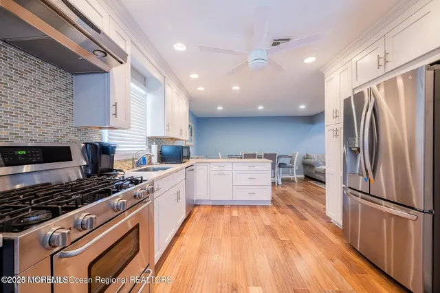 a kitchen with stainless steel appliances a refrigerator a stove a sink and white cabinets