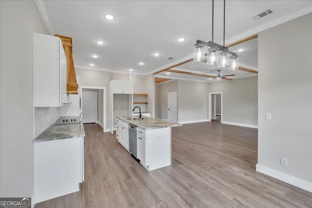 a large kitchen with kitchen island a stove a sink dishwasher a oven and a dining table with wooden floor