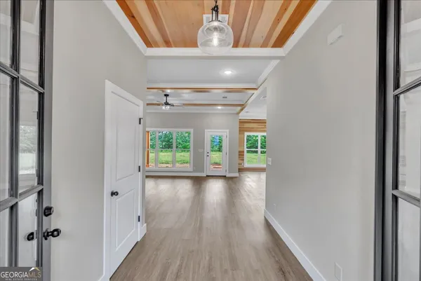 a view of a hallway to a livingroom with wooden floor and a window