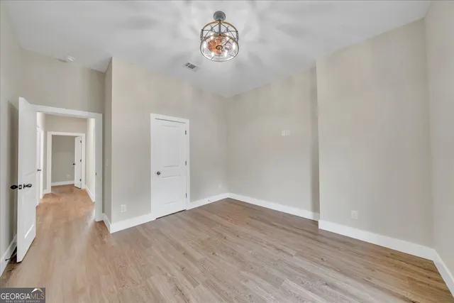 an empty room with wooden floor and a ceiling fan
