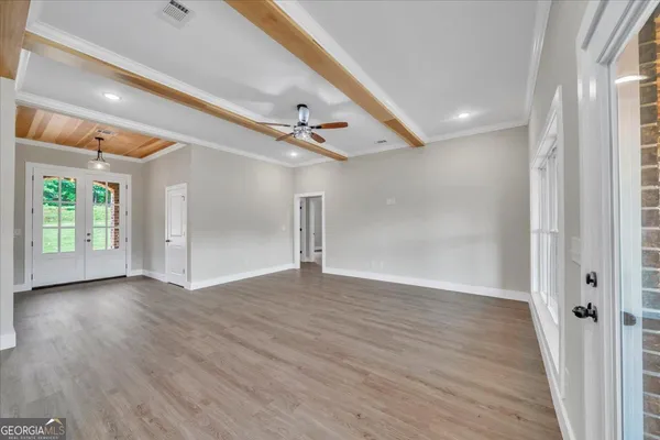 a view of an empty room with wooden floor and a window