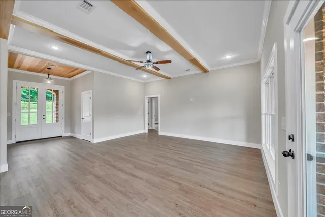 a view of an empty room with wooden floor and a window
