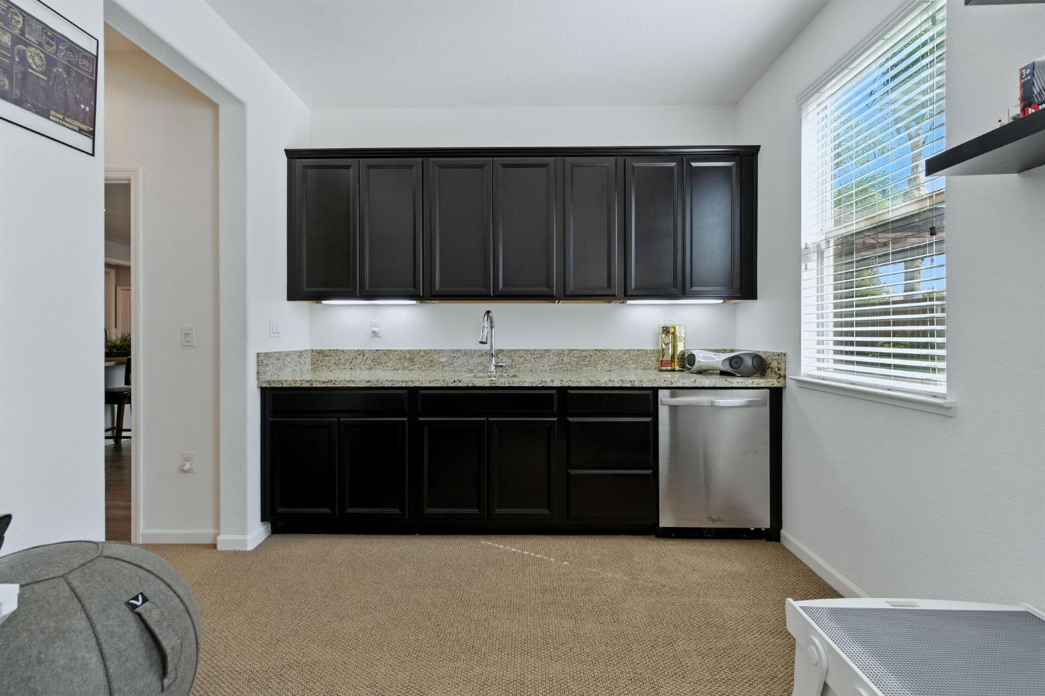 18200 Broadmoor Way Lathrop, CA 95330 - Photo 37 of 48 kitchen with dark cabinetry, light stone countertops, stainless steel dishwasher, and light colored carpet