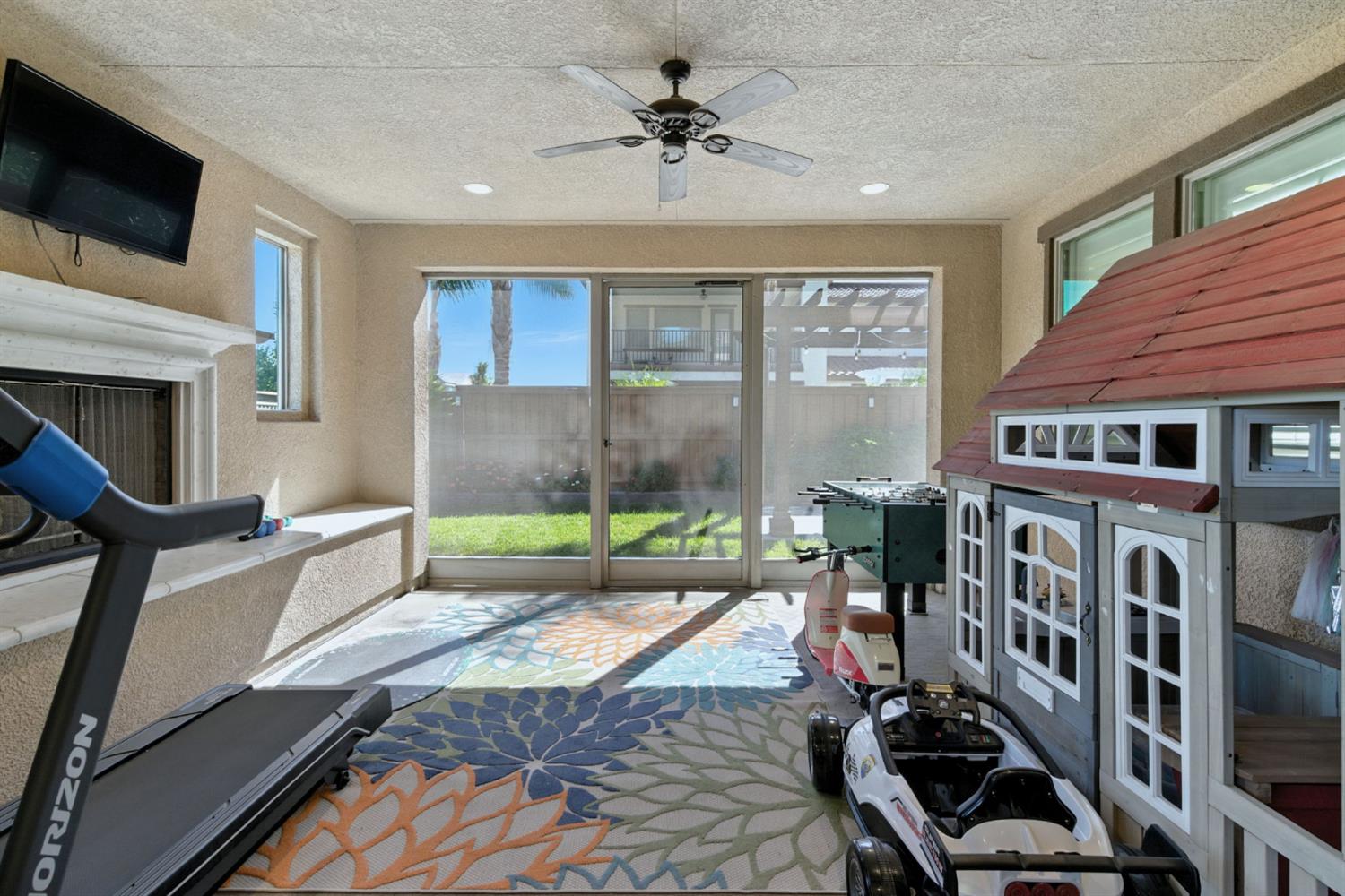 18200 Broadmoor Way Lathrop, CA 95330 - Photo 40 of 48 workout area with a textured wall, a ceiling fan, a textured ceiling, and a fireplace