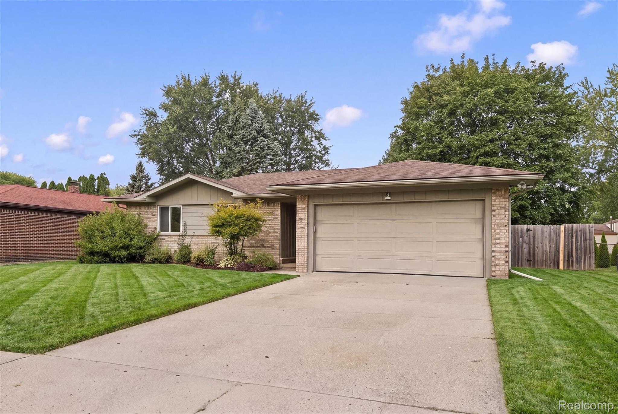 39861 Rager Court Clinton Township, MI 48038 - Photo 1 of 26 Single-story residence featuring a two-car garage, concrete driveway, and a front yard with mature trees